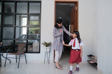 Okula dönelim. İlkokul üniformalı Asyalı öğrenci okula hazırlanıyor.