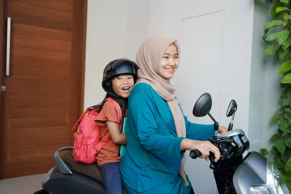 Ibu muslim membawa putrinya ke sekolah dengan sepeda motor di pagi hari — Stok Foto