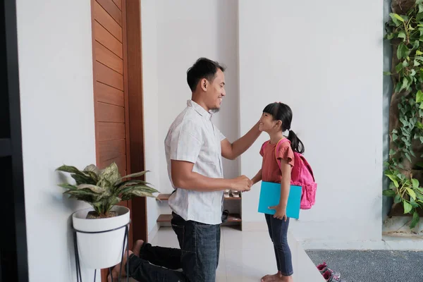 Endonezyalı ilkokul öğrencisi kız öğrenci okula gitmeden önce babasının elini sıkmış ve öpmüş. — Stok fotoğraf