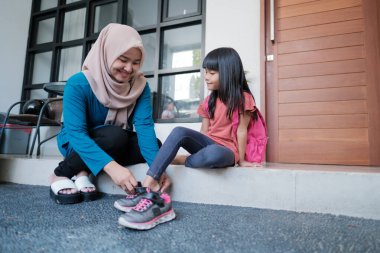 Anne, sabah kızının ayakkabı giymesine yardım et.