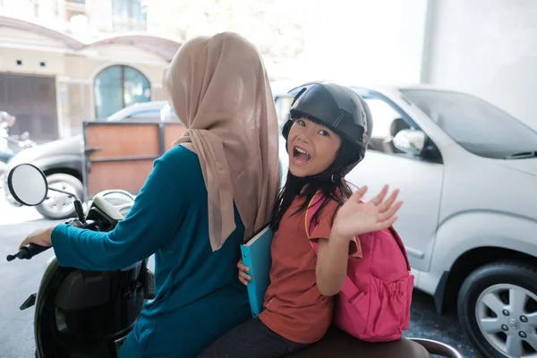 Moslim moeder neemt haar dochter naar school met de motor in de ochtend — Stockfoto