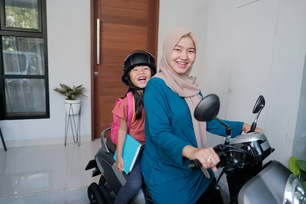 Müslüman anne sabah kızını motosikletle okula götürüyor. — Stok fotoğraf
