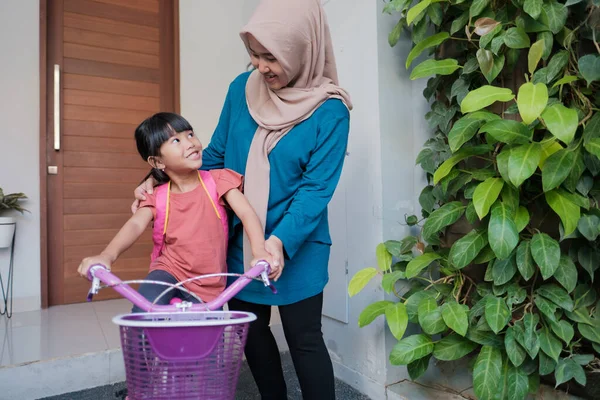 イスラム教徒と娘は自転車で学校に行く準備をしています — ストック写真