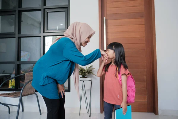 Anak sekolah dasar perempuan berjabat tangan dan mencium tangan ibu muslim nya — Stok Foto