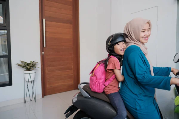 Müslüman anne sabah kızını motosikletle okula götürüyor. — Stok fotoğraf