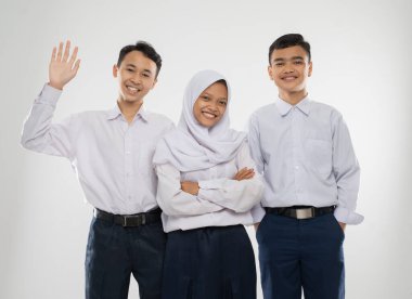 Ortaokul üniformalı üç genç ayağa kalktığında gülümseyerek selam veriyorlar.