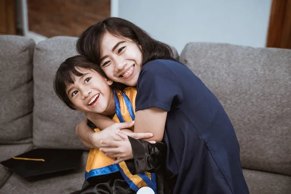 Orgullosa asiática madre abrazar su hija durante la escuela primaria graduación día —  Fotos de Stock