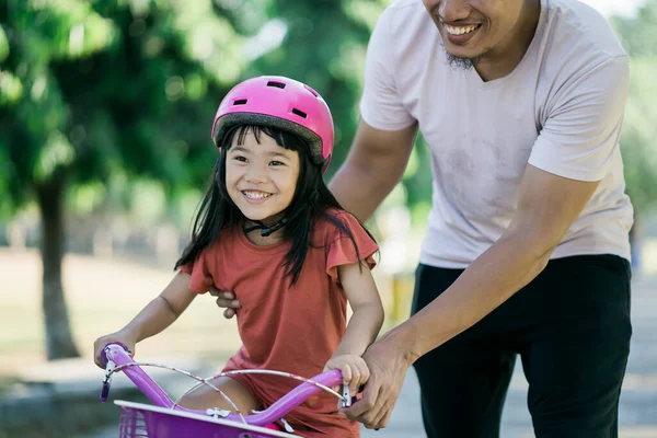 Pai ensinando filha a andar de bicicleta no parque — Fotografia de Stock