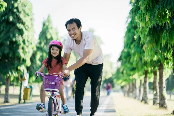 父は公園で自転車に乗るために娘を教える — ストック写真