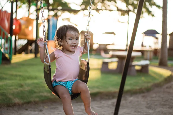 Asiatique fille jouer sur une balançoire et avoir du plaisir dans parc — Photo