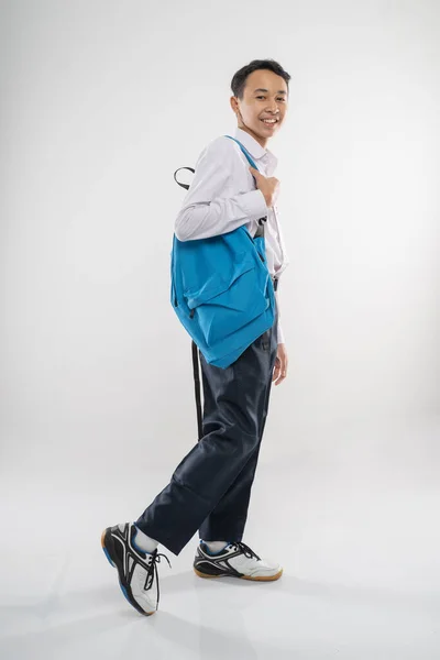 Un chico caminando en uniforme de secundaria sonriendo con una mochila — Foto de Stock