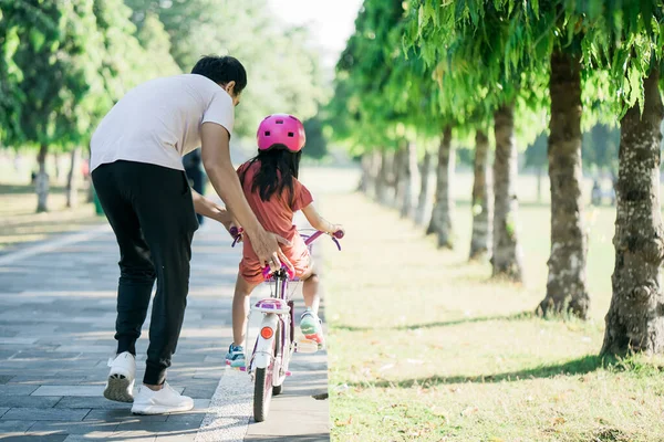 Отец учит дочь кататься на велосипеде в парке — стоковое фото