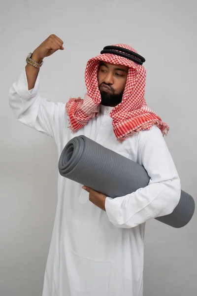 Arab noszący turban czuje ducha zaciskania pięści w górę, niosąc matę. — Zdjęcie stockowe