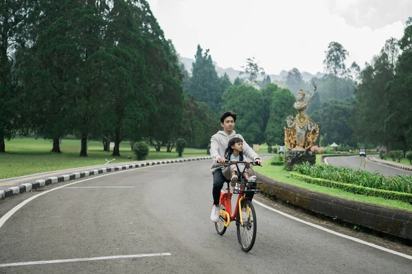 Bruder nimmt seine Schwester mit auf spaßiges Radfahren im Park — Stockfoto