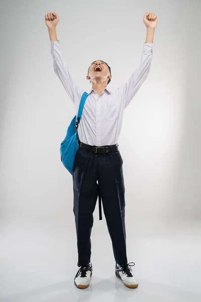 A boy raises his hand in a junior high school uniform in high spirits with a school bag — Stock Photo, Image