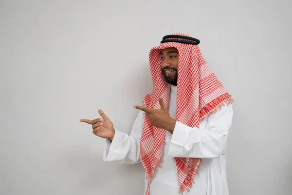 Arabska młodzież w turbanie uśmiechnięta, stojąca z gestem wskazującym na coś — Zdjęcie stockowe