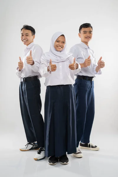 Tre tonåringar bär junior gymnasiet uniformer stående med tummen upp — Stockfoto