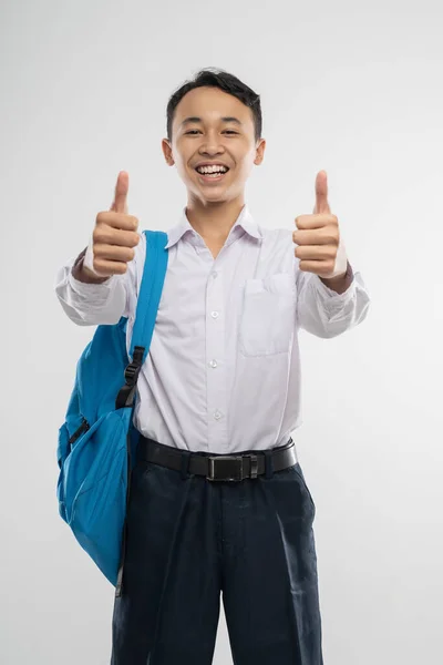 Un hombre sonriente con uniforme escolar y una mochila con pulgares arriba — Foto de Stock