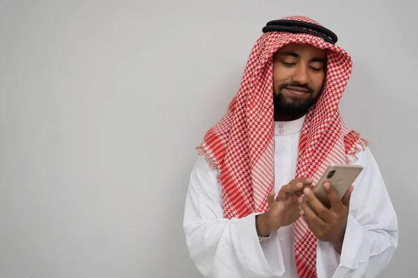 Un jeune Arabe dans un turban utilisant un téléphone portable essuyant l'écran tout en souriant — Photo