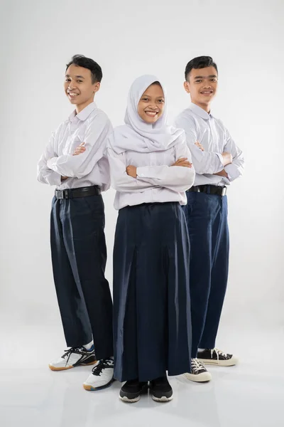 Tre tonåringar i junior gymnasiet uniformer stående med korsade händer — Stockfoto