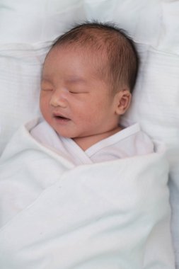 Doğumhanedeki battaniyede uyuyan yeni doğmuş bir bebek.