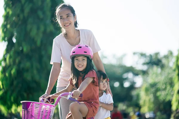 Madre enseñando a su hija a andar en bicicleta en el parque —  Fotos de Stock