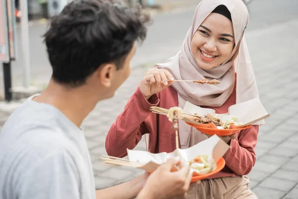 Pasangan menikmati sate ayam yang mereka beli dari penjual makanan jalanan di indonesia — Stok Foto