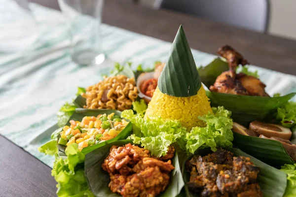 Νάσι Τάμπενγκ. Ινδονησία κουζίνα κίτρινο ρύζι σε φύλλα μπανάνας — Φωτογραφία Αρχείου