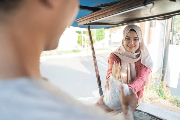 Muslimische Frau nimmt ihre Essensbestellung von Chicken Satay — Stockfoto