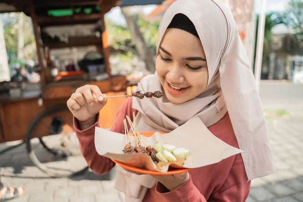 Wanita muslim memesan sate ayam dari penjual gerobak makanan kecil. — Stok Foto