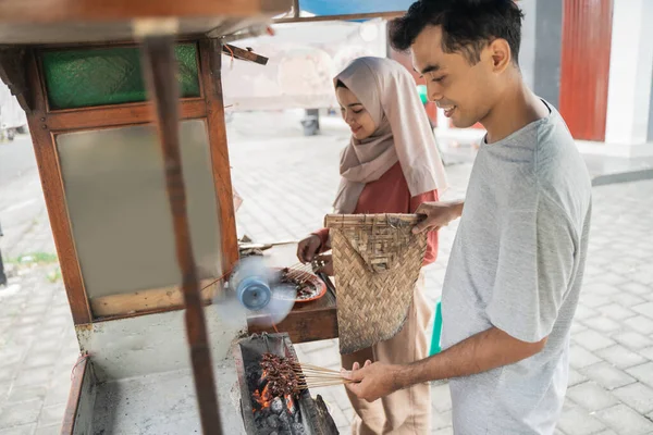 Dva prodejci připravují jídlo na stánku s jídlem, kde prodávají tradiční kuřecí satay — Stock fotografie
