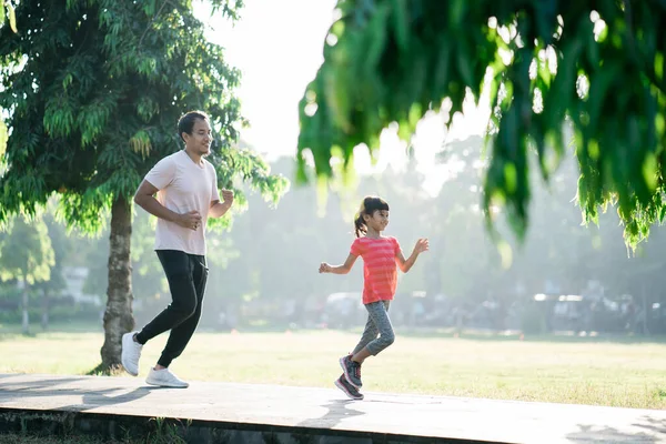 Padre e hija pequeña hacen ejercicios al aire libre. Estilo de vida saludable de la familia con el niño —  Fotos de Stock