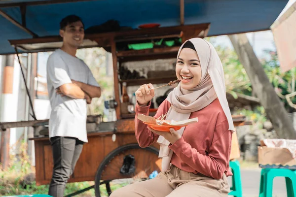 Musulmana mujer ordenar pollo satay de pequeño carrito de comida vendedor. — Foto de Stock