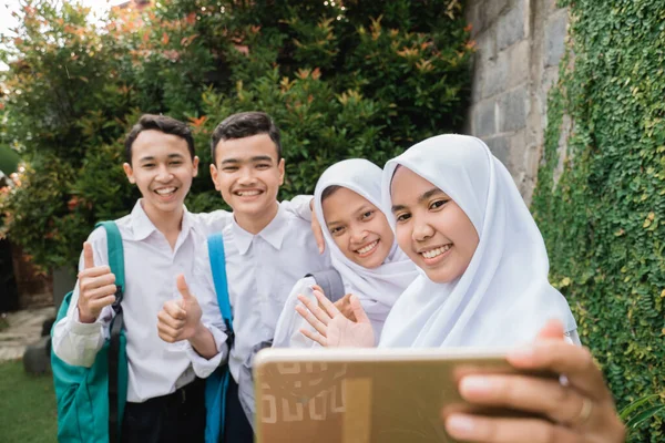 Quatro adolescentes em uniformes do ensino médio júnior tomando selfie juntos usando um smartphone — Fotografia de Stock