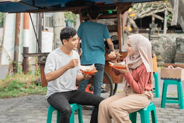 Pasangan menikmati sate ayam yang mereka beli dari penjual makanan jalanan di indonesia — Stok Foto