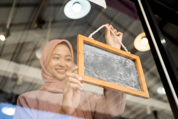 Hezká dívka v šátku na hlavě postaví na okenní tabuli tabuli — Stock fotografie