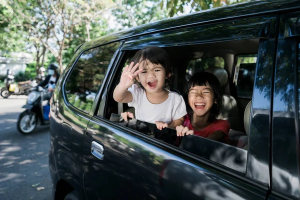 窓から手を振って車で移動するアジアの兄弟たち — ストック写真