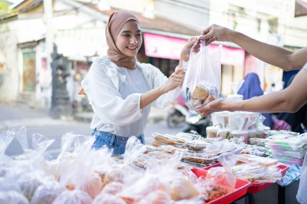 ベールの中の美しい女の子は道端の屋台の売り手からTakjil食品を購入します — ストック写真