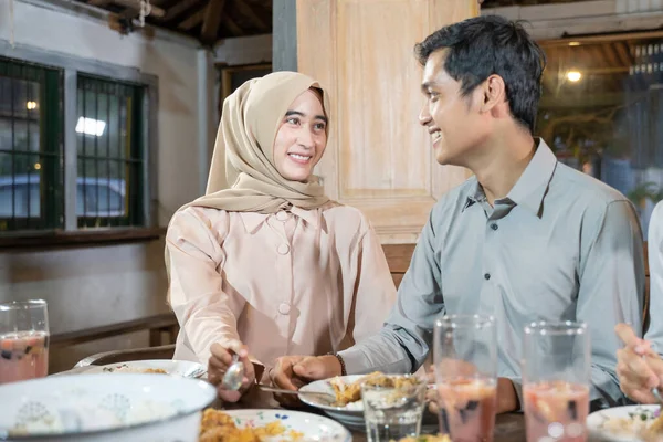 Um homem e uma mulher no hijab olham um para o outro enquanto tomam acompanhamentos juntos durante o iftar — Fotografia de Stock