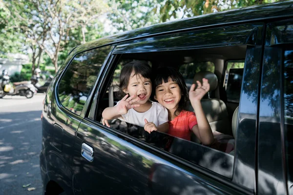 Asiatiques frères et sœurs agitant les mains de la fenêtre et Voyage en voiture — Photo
