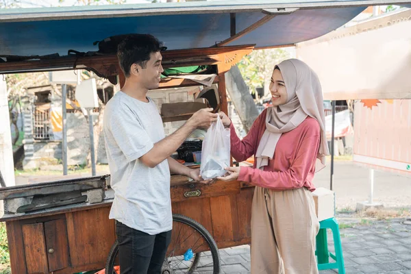 Moslim vrouw neemt haar bestelling eten van kip saté — Stockfoto