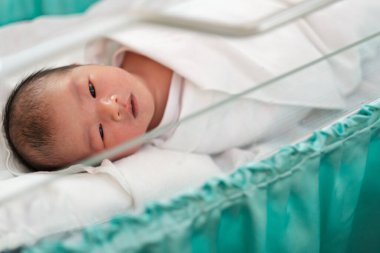 Doğumhanedeki battaniyede uyuyan yeni doğmuş bir bebek.