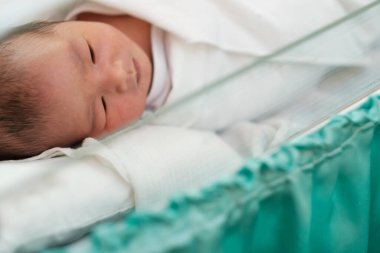 Doğumhanedeki battaniyede uyuyan yeni doğmuş bir bebek.
