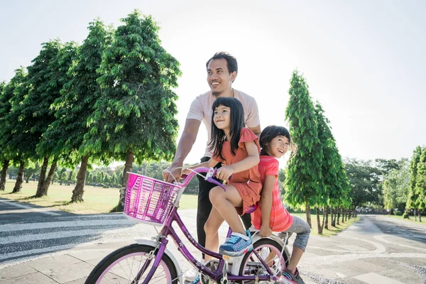 Ojciec uczy córkę jeździć na rowerze w parku — Zdjęcie stockowe