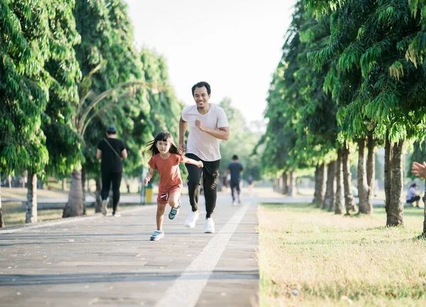 Padre e hija pequeña hacen ejercicios al aire libre. Estilo de vida saludable de la familia con el niño —  Fotos de Stock