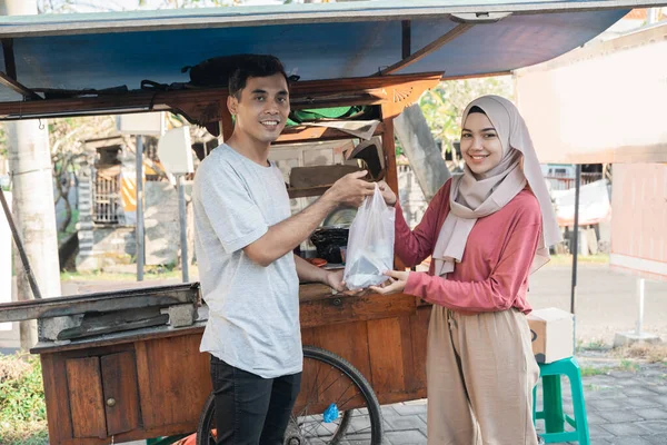Muslimsk kvinna beställer kyckling satay från liten matvagn säljare. — Stockfoto