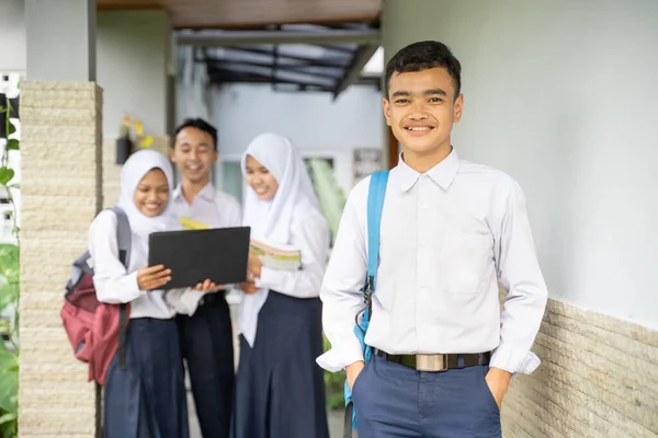 Teenager se usměje na kameru ve školní uniformě nesoucí školní tašku s kopírovacím prostorem — Stock fotografie