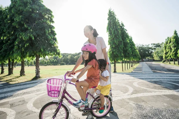 Mãe Ensinando filha a andar de bicicleta no parque — Fotografia de Stock