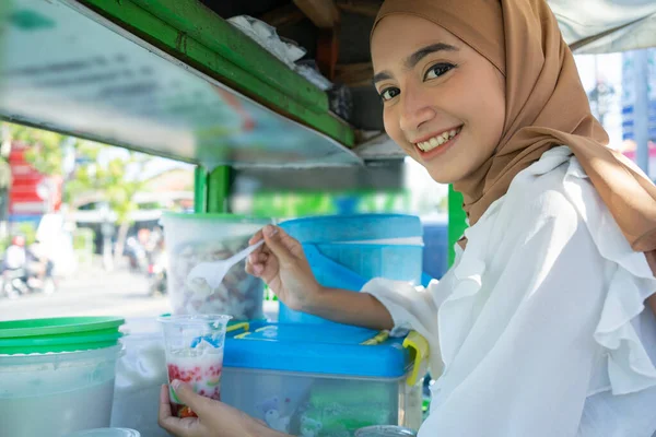 Hezká dívka v závoji prodává campur pomocí lžíce, aby si rýžovou kaši — Stock fotografie