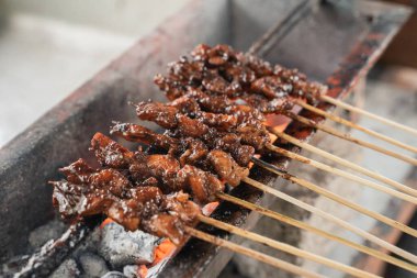 Sate ayam geleneksel satay şiş mangal kömürü kullanılarak kızartılıyor.